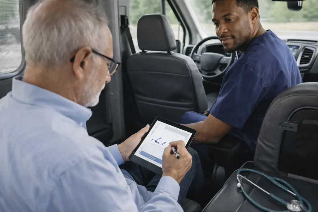 Patient signing NEMT trip form as proof of service in medical transportation vehicle